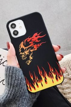 a woman is holding up her phone case with flames on the back and skull design