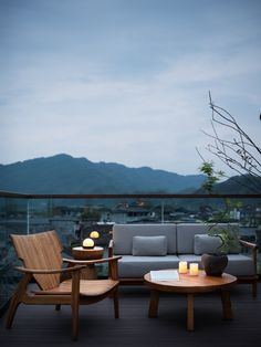 two wooden chairs sitting on top of a balcony next to a table with candles in it