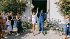 a man and woman are walking down the street with their arms in the air as confetti is thrown around them