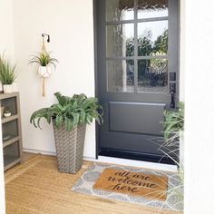 a welcome mat and potted plants in front of a door