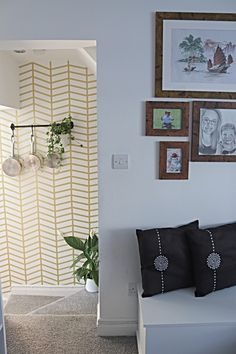 a white bench sitting in the middle of a living room next to a wall with pictures on it