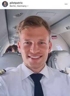 a man in uniform is smiling while sitting on an airplane with other people behind him