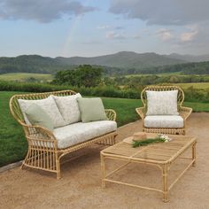 two wicker couches and a coffee table on a patio with mountains in the background