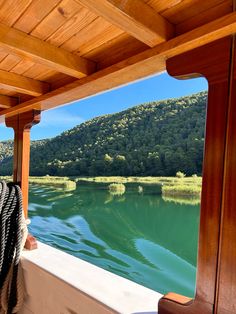 a person sitting on a boat looking out at the water and mountains in the distance