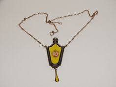 "This RARE antique chatelaine perfume pendant necklace is hard to find item chartered 1867 University of Illinois sterling Silver Enamel Perfume bottle necklace. It has vibrant colors of yellow, green leaves and one pink flower against a black border and a sterling carved vine leaf pattern decor. The necklace is 18 inches long. The perfume bottle is 2 3/4\" inches long including the drop x 1\" inch wide. The top of the lid is marked \"sterling\" and the dauber is attached to the lid. No dents or Antique Enamel Locket Necklace, Victorian Enamel Medallion Necklaces, Antique Yellow Jewelry Collectible, Antique Yellow Collectible Jewelry, Antique Enamel Necklace For Formal Occasions, Vintage Enamel Necklaces With Lobster Clasp, Victorian Enamel Necklace For Gifts, Victorian Enamel Necklace For Gift, Victorian Enamel Necklaces For Gifts