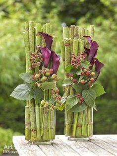 two vases filled with flowers sitting on top of a wooden table next to each other