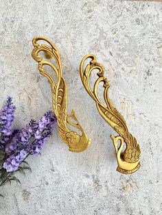 two golden metal handles sitting next to purple flowers