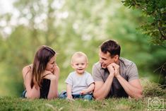 a man, woman and child are sitting in the grass with their hands on their chins