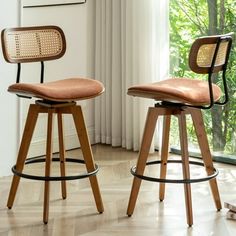 two wooden barstools in front of a window with curtains on the windowsill