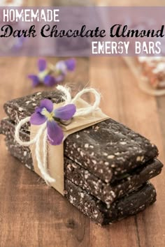 homemade dark chocolate almond energy bars stacked on top of each other with purple flowers in the background