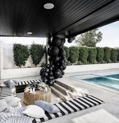 black and white balloons are hanging from the ceiling near a pool with striped rugs