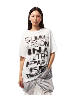 This T-shirt features a bold, blurry graphic that makes a strong visual impact. The oversized cut offers a relaxed and modern silhouette, while the graphic adds an artistic and edgy touch. It's a statement piece that combines comfort with a strong fashion sense, perfect for a casual yet stylish look.  - The T-shirt's graphic evokes the look of street-style graffiti, giving it an urban vibe.- The stark contrast between the background color of the T-shirt and the graphic print ensures the design stands out.- Its length makes it versatile enough to be worn as a dress or paired with leggings or pants.- The blurred lettering adds a sense of motion and mystery, leaving the interpretation open to the viewer. Oversized Modern T-shirt For Summer, Modern Oversized T-shirt For Summer, Modern Text Print Tops For Summer, Modern Summer Top With Text Print, Modern Graphic Print T-shirt For Summer, Modern Graphic Print T-shirt For Spring, Modern Letter Print T-shirt For Spring, Modern Summer T-shirt With Graphic Design, Urban Boxy Fit T-shirt For Summer