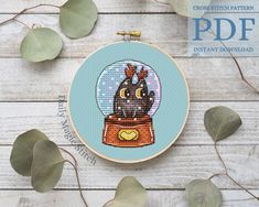 a cross stitch pattern with an owl in a glass ball on top of a wooden table