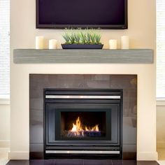 a flat screen tv mounted above a fire place in a living room with candles on the mantle