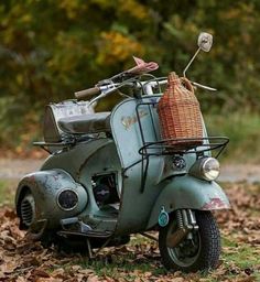 an old scooter with a basket on the back is parked in some leaves