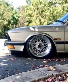 a silver car parked on the side of a road next to some leaves and trees