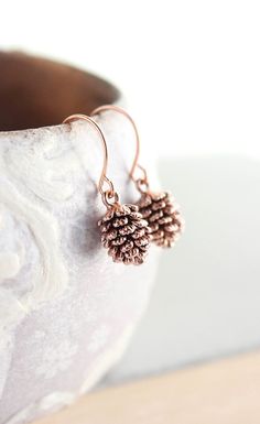 These are rustic nature inspired antiqued rose gold pine cone earrings! These little drop earrings have beautiful details highlighted by the antiqued rose gold over brass finish! These earrings are nickel free and lightweight, making them great for everyday wear.  The fish hook ear wires are rose gold over brass and are nickel free.  These earrings measure approximately 1(26mm) long and the pine cone charm is approximately .5 (12mm). These are available in antique silver and antiqued gold (as... Pine Cone Earrings, Pinecone Earrings, Horn Pendant Necklace, Long Pearl Necklaces, Horn Pendant, Moon Pendant Necklace, Pearl Jewelry Necklace, Swarovski Necklace, Rhinestone Designs