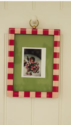 a green and red frame hanging on a white wall with flowers in the center,