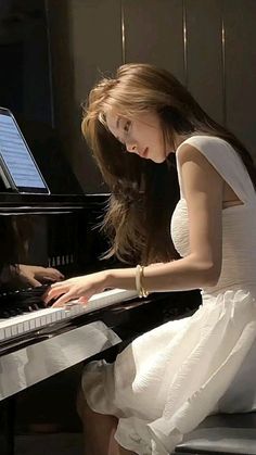 a woman in a white dress playing the piano