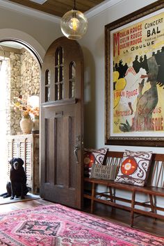 a dog sitting in front of a wooden door with a poster on the wall behind it