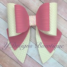 a bow made out of paper on top of a wooden floor with the words designs boutique