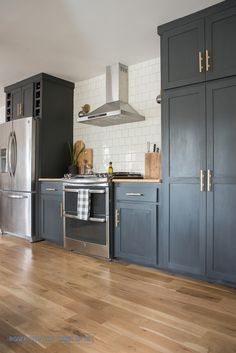 a kitchen with blue cabinets and stainless steel appliances, including an oven hood over the range