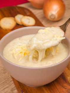 a spoon full of soup on top of a wooden cutting board next to onion slices