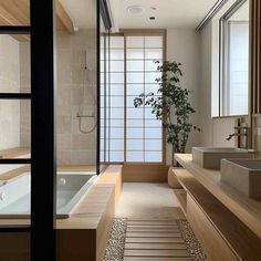 a large bathroom with two sinks and a bathtub in the middle, along with a bamboo plant