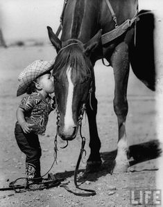 a little boy that is standing next to a horse