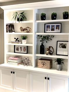 a white bookcase filled with lots of books and potted plants on top of it