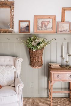 a living room with pictures on the wall and a chair next to a table in front of it