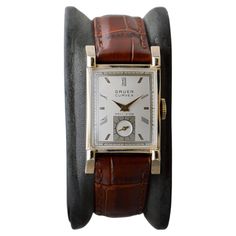 FACTORY / HOUSE: Gruen Watch Company STYLE / REFERENCE: Art Deco / Reference 705 METAL / MATERIAL: 10Kt Gold Filled CIRCA / YEAR: 1940's DIMENSIONS / SIZE: Length 38mm X 22mm Width MOVEMENT / CALIBER: Manual Winding / 16 Jewels / Caliber 335 DIAL / HANDS: Factory Original Dial with Baton and Roman Numeral Gilt Markers / Gilt Hands ATTACHMENT / LENGTH: Leather, 16mm / Regular Length WARRANTY: 18 months on the movement This is a "vault find" watch, it has been locked up for nearly 50 years, which Gruen Watches, Factory House, Art Deco Watch, Tank Watch, Reference Art, Style Reference, Watch Dial, Style Watch, Watch Companies