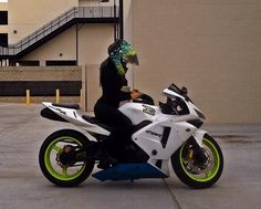 a person sitting on top of a white and green motorcycle in front of a building