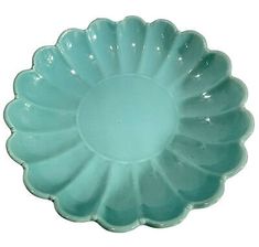 a green glass bowl sitting on top of a white table