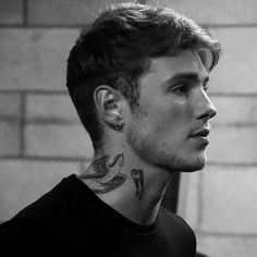 black and white photograph of a man with tattoos on his neck looking off into the distance