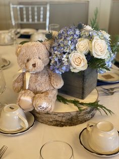 a teddy bear sitting on top of a table next to a vase filled with flowers