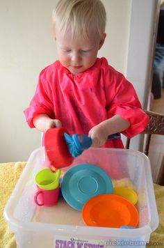 a young child playing with toys in a plastic container