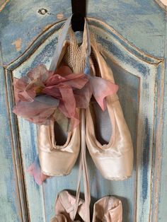 several pairs of ballet shoes hanging on a door hanger with tulle de chine