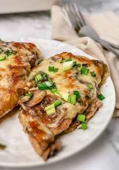 two pieces of pizza on a white plate with green onions and scallions next to it