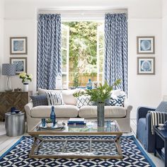 a living room with blue and white decor on the walls, couches, coffee table and windows