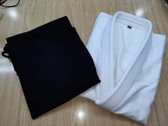 two pairs of white and black clothing sitting on top of a wooden floor next to each other