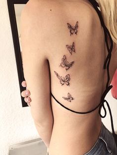 a woman's back with three butterflies on her left side, and the bottom part of her body visible