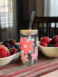 a glass cup with strawberries and raspberries next to it on a table