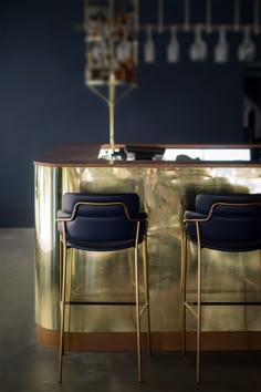 two blue chairs sitting at a bar in front of a gold counter with an umbrella