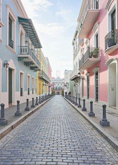 a cobblestone street lined with tall buildings and balconies on either side