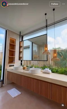 a bathroom with two sinks and large windows looking out onto the yard outside at sunset