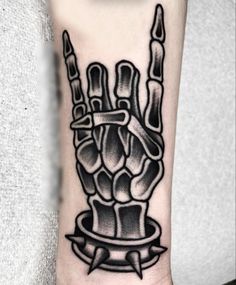 a black and white tattoo on the wrist of a person with a hand holding two knives