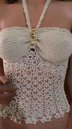 a woman wearing a white crochet top with gold chains on her neck and chest