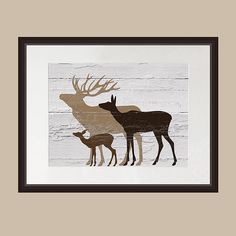 two deer standing next to each other in front of a wooden wall with a black frame