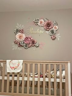 a baby's room with a crib and flowers on the wall